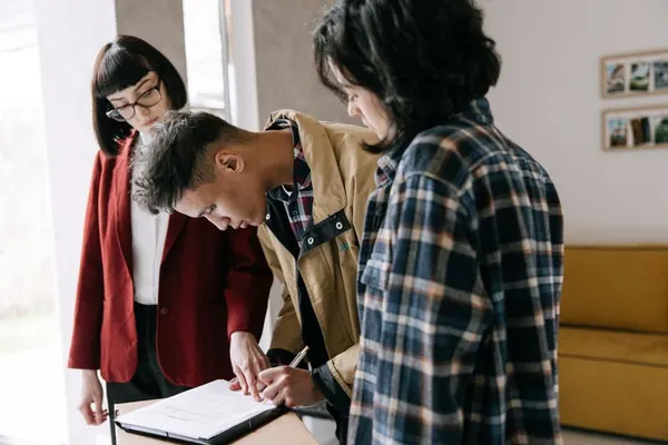 Tres personas revisan la firma de un documento