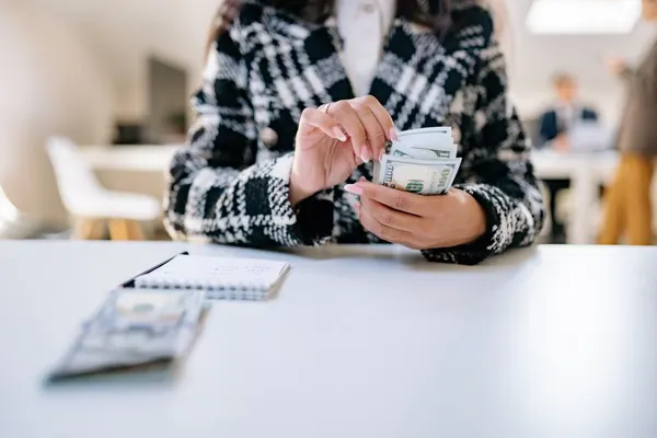 Una persona cuenta billetes sobre una mesa de trabajo