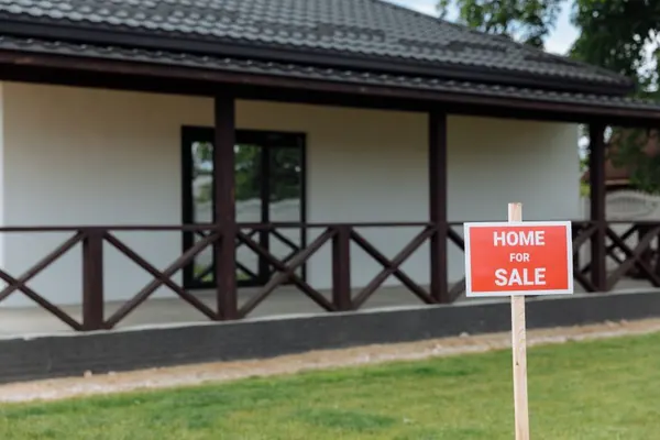 Una casa con un cartel de se vende en el jardín