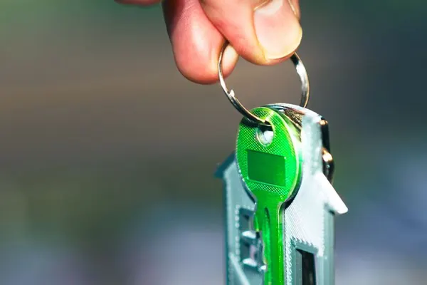 Una mano sostiene unas llaves con un llavero en forma de casa